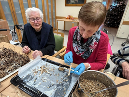 Zwei Frauen basteln mit Naturmaterialien an einem Tisch.