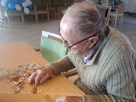 Ein älterer Mann sortiert Buchstaben auf einem Tisch.