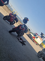 Ein Motorrad steht neben einem gestürzten Fahrer auf dem Asphalt.