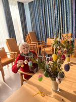 Eine ältere Frau dekoriert einen Osternbaum mit bunten Eiern.