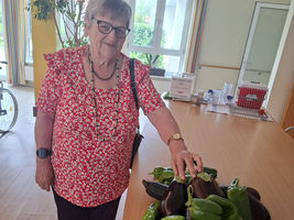 Eine ältere Frau steht an einem Tisch mit frischem Gemüse.