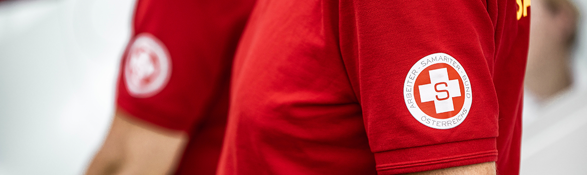 Rotes Shirt mit einem Abzeichen des Arbeiter-Samariter-Bundes Österreichs.