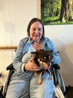 Eine Frau im Rollstuhl hält einen Chihuahua auf ihrem Schoß.