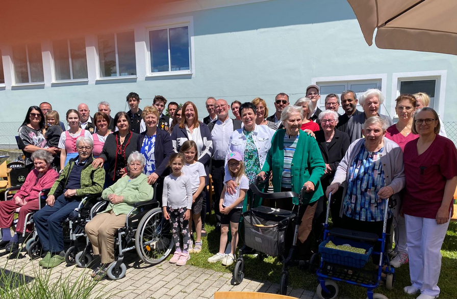 Eine Gruppe von Menschen, älteren Erwachsenen und Kindern, lächelt auf einem Foto.