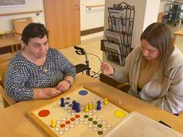 Zwei Frauen spielen ein Brettspiel in einem gemütlichen Raum.
