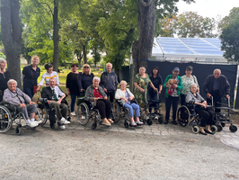 Gruppe von älteren Menschen in Rollstühlen, die im Freien posieren.