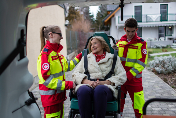 Patientin im Krankentransportstuhl mit zwei Samariterbund-Sanitäter:innen