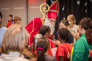 Sankt Nikolaus interagiert mit Kindern in festlicher Atmosphäre.