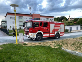 Rotes Feuerwehrauto steht auf einem Weg vor Wohnhäusern.