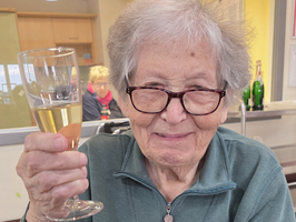 Eine ältere Frau hebt ein Glas Sekt zum Feiern.
