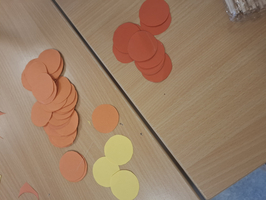 Stapelhaufen aus orangefarbenen und gelben Papierkreisen auf einem Tisch.