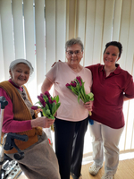 Drei Frauen lächeln und halten Tulpen in ihren Händen.