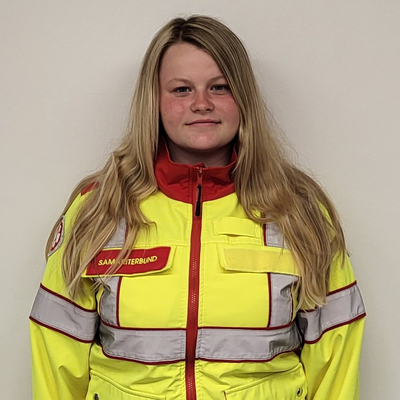 Junge Frau trägt eine auffällige gelbe, rote und graue Rettungsjacke.