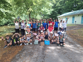 Eine Gruppe von Kindern und Erwachsenen mit erhobenen Armen im Freien.
