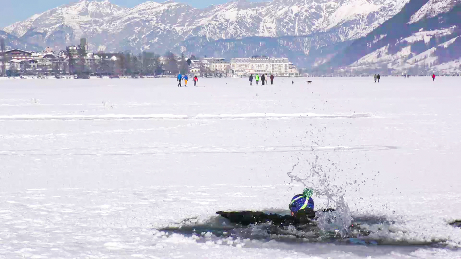 Ein Sprung ins Eiswasser mit schneebedeckten Bergen im Hintergrund.