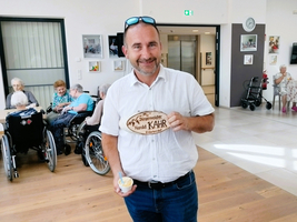 Ein Mann hält ein Holzschild mit der Aufschrift 