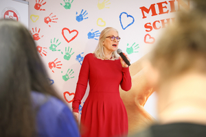 Susanne Drapalik, Präsidentin des Samariterbunds Wien, spricht vor DIF-Hintergrund im LernLEO GSG in ein Mikrofon