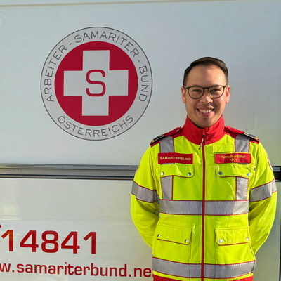 Ein Sanitäter in Uniform steht vor einem Rettungsauto des Samariterbundes.