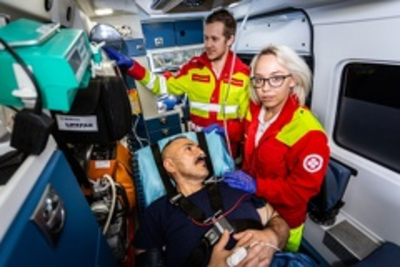 Sanitäterin mit Patienten im Rettungswagen, Samariterbund-Kollege im Hintergrund