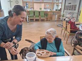Eine Frau interagiert mit einem Hund in einer Gemeinschaftseinrichtung.
