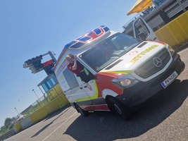 Rettungswagen steht auf einer Rennstrecke mit einem Gesundheitshelfer am Fenster.