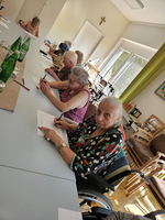 Ältere Menschen sitzen an einem Tisch und schreiben auf Papier.
