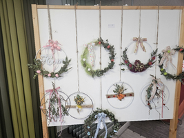Sechs dekorative Kränze aus Blumen und Zweigen an einer Wand aufgehängt.