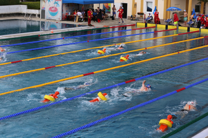 Schwimmer in einem Becken, unterstützt durch Schwimmhilfen und Trainingselemente.