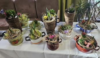 Bunte Blumenkübel mit frischen Pflanzen und Osterdekoration auf einem Tisch.