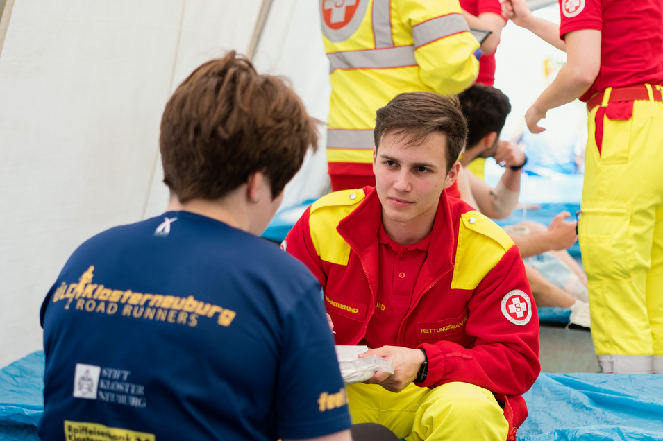 Rettungssanitäter spricht mit Patient im Einsatzzelt des Vienna City Marathons