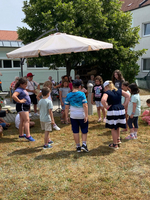 Eine Gruppe von Kindern spielt zusammen im Freien unter einem Sonnenschirm.