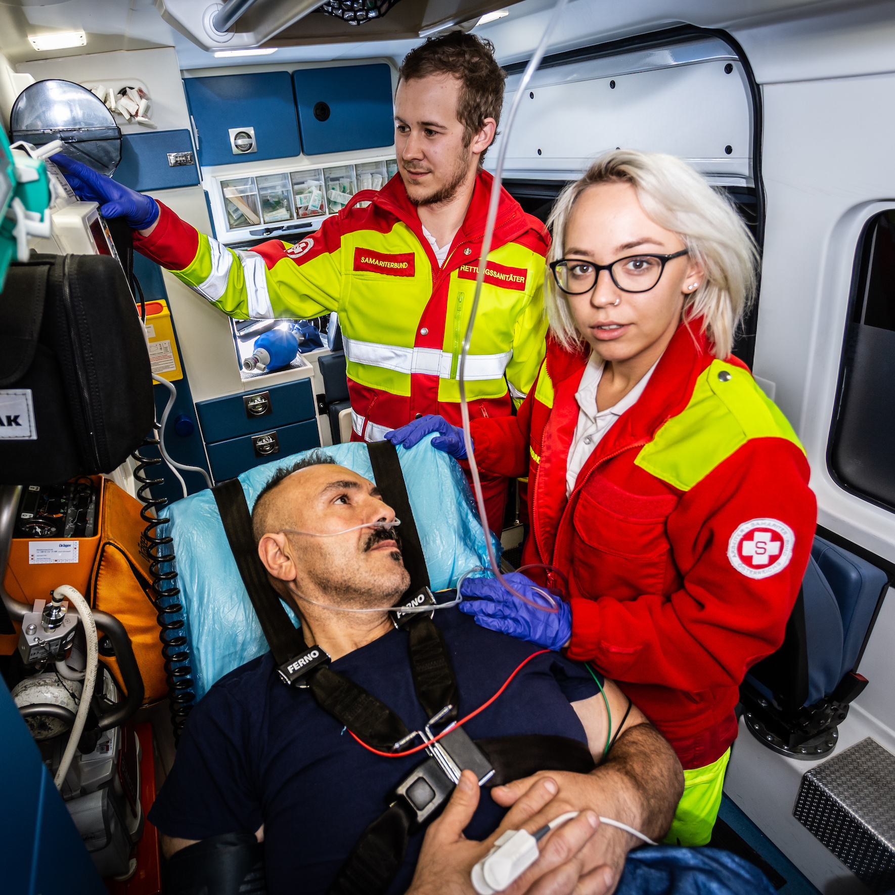 Rettungssanitäterin mit Patienten, Kollege im Hintergrund
