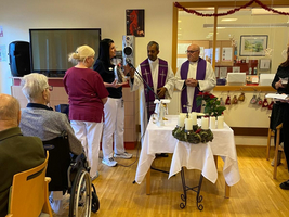 Gottesdienst mit Priester und Gemeindemitgliedern in einem festlichen Raum.