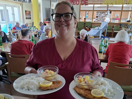 Eine Frau in scharlachrotem Outfit trägt zwei Teller mit Essen.