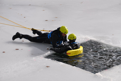 Rettung von einer Person im Wasser durch einen Helfer auf Eis.