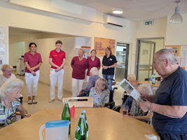 Ältere Menschen sitzen beim Treffen mit Pflegekräften in einem Aufenthaltsraum.