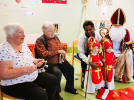 Zwei kleinen Kinder in Märchenkostümen stehen neben Erwachsenen in einem Raum.
