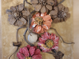 Eine dekorative Anordnung aus verschiedenen getrockneten Blumen in verschiedenen Farben, ergänzt durch einige runde Elemente und geschwungene Äste. Die Blumen zeigen verschiedene Formen und Texturen, vor allem in Rosatönen und Erdtönen. Der Hintergrund ist neutral und hebt die floralen Elemente hervor.