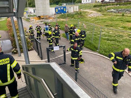 Feuerwehrleute in Schutzkleidung versammeln sich vor einem Gebäude.
