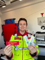 Ein Notfallsanitäter hält ein Namensschild und Venenverweilkanülen in der Hand.