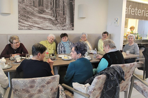 Eine Gruppe älterer Frauen bei einem geselligen Treffen in einem Speisesaal.