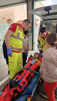 Zwei Sanitäter schnallen ein Kind in eine Vakuummatratze an.