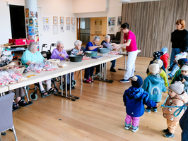 Ältere Menschen und Kinder arbeiten gemeinsam an einem Bastelprojekt.