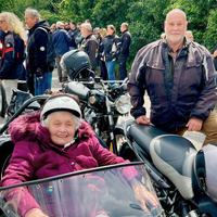 Eine ältere Frau sitzt in einem Motorradgespann und lächelt glücklich.
