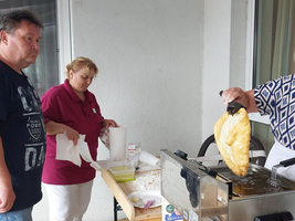Drei Personen bereiten frische Speisen in einer Küche im Freien zu.