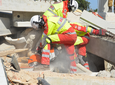 Rettungskräfte schneiden Beton in einer Trümmerlandschaft. Staub возле ближайших.