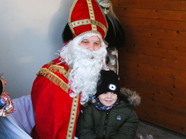 Der Nikolaus posiert mit einem lächelnden Kind in warmer Kleidung.
