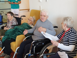 Ältere Frauen in Rollstühlen unterhalten sich freundlich in einem Gemeinschaftsraum.