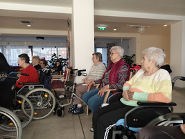 Eine Gruppe älterer Frauen sitzt in Rollstühlen in einem Raum.