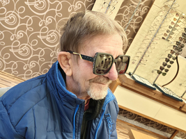 älterer Mann mit Brille sitzt in einem Geschäft für Brillen.